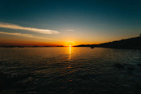 An orange and blue sunset over the spanish coast with dark silhouettesの写真素材