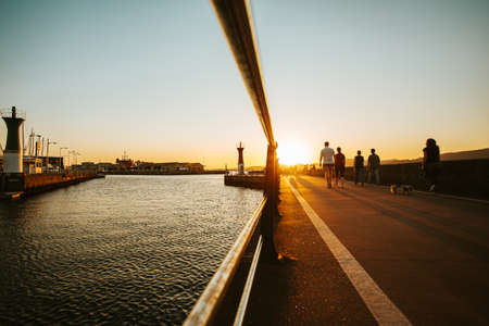 The walk on the docks to the lighthouse during a burning sunset with people walking byの写真素材