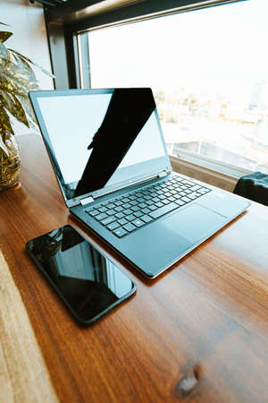 A work space composition with a black mobile phone and a black laptopの写真素材
