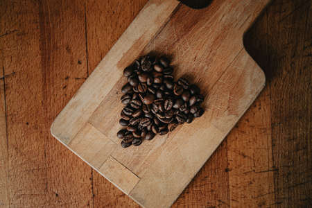 A flat lay of a heart symbol made of coffee grains over two wood tablesの写真素材