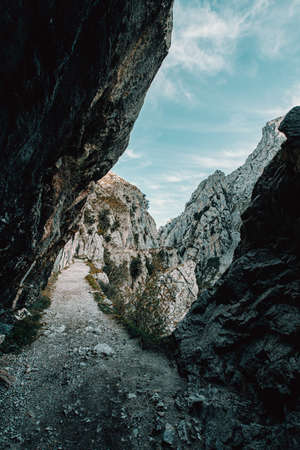 A hiking path in the middle of the rocky mountains with the cliffs nearの写真素材
