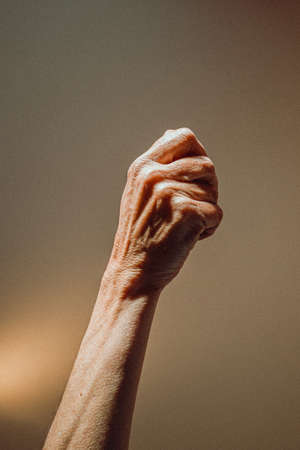 An old woman closed hand rising on pastel tones with lightsの写真素材