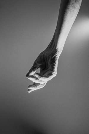 One old hand hangs from the top of the image in black and whiteの写真素材