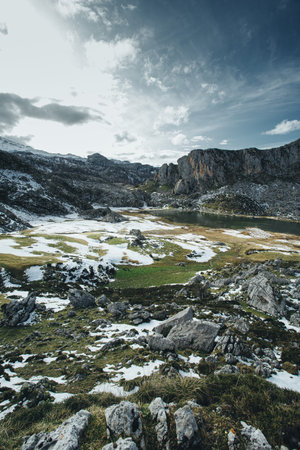 A wide angle shot of a massive mountain with a frozen lake in front covered in snowの写真素材