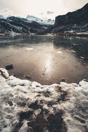 A super close up of a frozen lake in covadonga with the mountains in the background during a sunny dayの写真素材