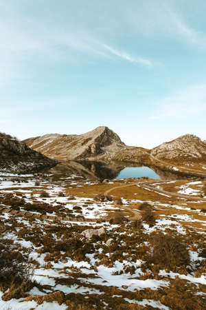The lake Enol in asturias during a sunny and snowed day in spainの写真素材