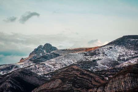 The mountain range being touched by the sun during the sunset with snowの写真素材