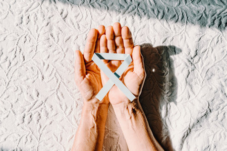 An vertical image of two old hands grabbing a blue ribbon for the international diabetes day