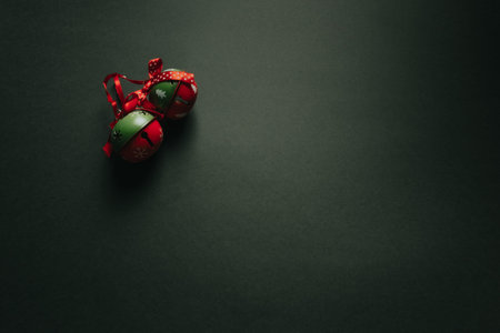 A christmas flat lay with two jingle bells over a dark background with copy space