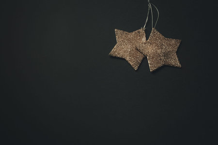 A christmas flat lay with two golden stars over a dark background with copy space
