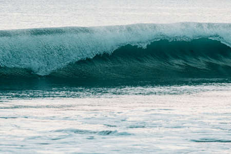 A massive surfing wave crashing into the sea during a bright day with copy spaceの写真素材