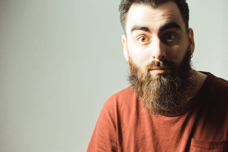 A young hipster style man with a beard and modern haircut surprised with copy spaceの写真素材