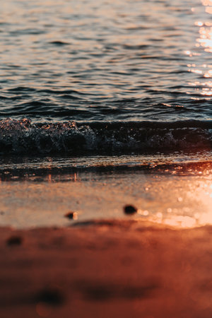 A massive sunset over the islands reflecting over the ocean with the sun and the tides on the beach over the sand during spring, on colorful tones with copy spaceの写真素材