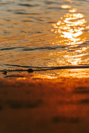 A massive sunset over the islands reflecting over the ocean with the sun and the tides on the beach over the sand during spring, on colorful tones with copy spaceの写真素材
