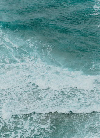 Aerial view of the ocean with the waves and re rocks during a bright day, relaxing scene on blue tonesの写真素材