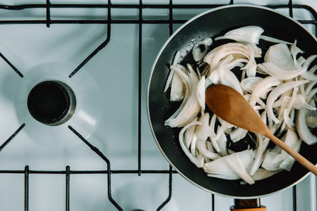 An aerial pan filled with grilled onions and a wooden spoonの写真素材
