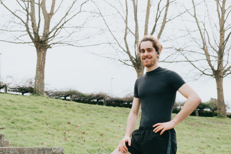 A young athletic male smiling to camera while doing exercise at the park with copy spaceの写真素材
