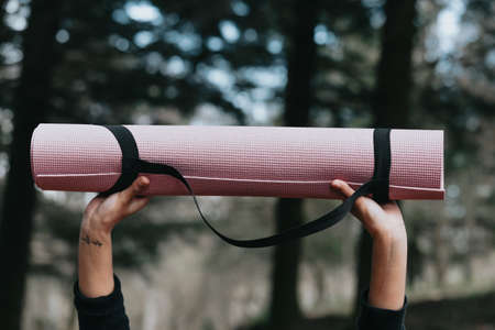 Two hands grabbing a yoga mat in the air on the forest relaxing conceptの写真素材