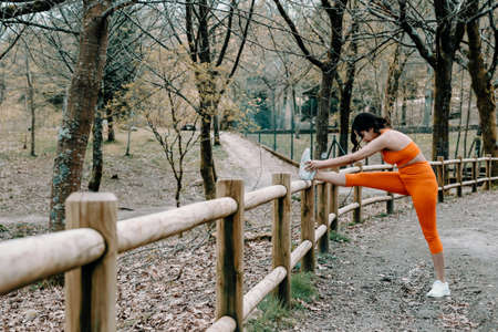 Young woman in fitness clothes stretching his body at the park with copy spaceの写真素材