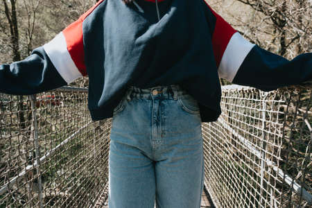 A close up of a woman wearing mom jeans on a bridge over the riverの写真素材