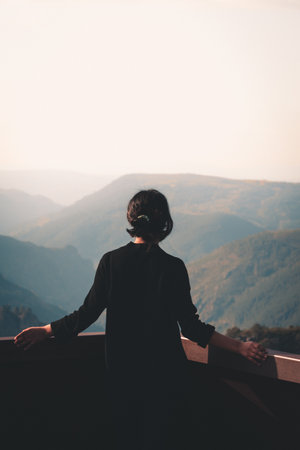A young woman in front of massive mountains looking to the horizon during a sunny day wellness and liberty conceptの写真素材