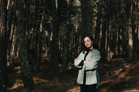 Young woman looking to camera in the middle of a pine forest with copy space reflection concept