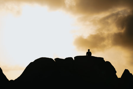Silhouette of a man over a mountain during a blue hour sunset with copy space, liberty and reflection conceptsの写真素材