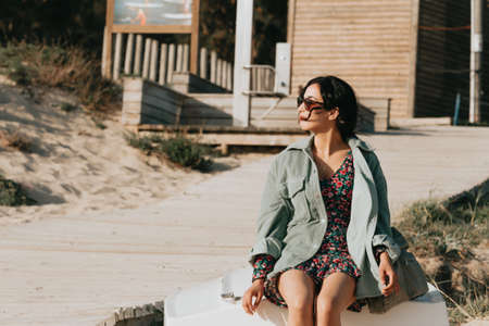 Woman smiling on the beach looking to camera while using sunglasses summer concept lifestyleの写真素材