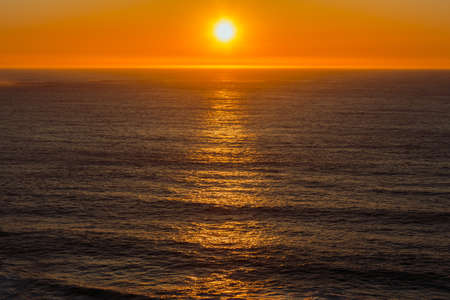 Massive colorful sunset over the ocean during a bright day aerial shotの写真素材