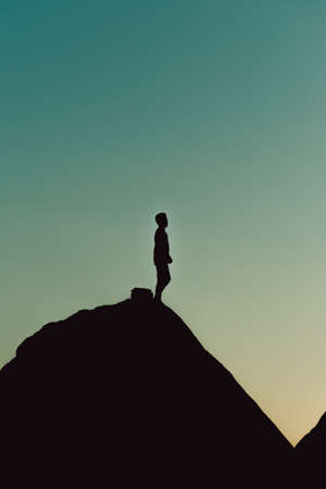 Silhouette of a man over a mountain during a blue hour sunset with copy space, liberty and reflection conceptsの写真素材