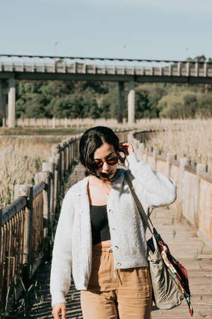 Woman using sunglasses smiling to camera while on the country yard during a super sunny day with copy space and lifestyle shotの写真素材