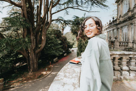 Young woman smiling to camera with copy space while holding a bunch of booksの写真素材