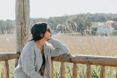 Woman using sunglasses smiling to camera while on the country yard during a super sunny day with copy space and lifestyle shotの写真素材