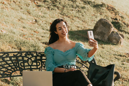 Young woman taking a selfie on a bench of the park lifestyle concept summer styleの写真素材