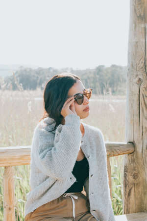 Woman using sunglasses smiling to camera while on the country yard during a super sunny day with copy space and lifestyle shotの写真素材