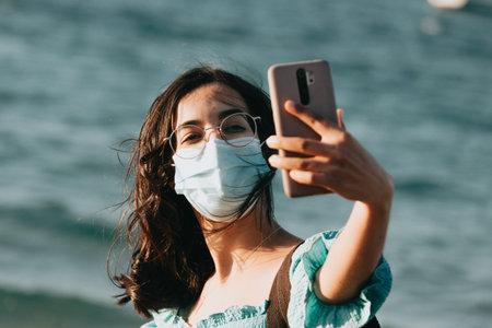 Young woman on the beach using a mask while taking a selfie lifestyle concept summer style