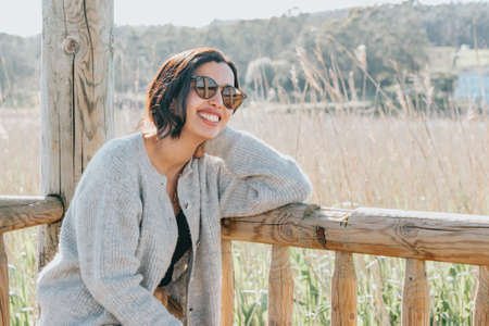 Woman using sunglasses smiling to camera while on the country yard during a super sunny day with copy space and lifestyle shotの写真素材