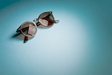 Pair of sunglasses over a pastel blue with lights reflecting background with copy space minimal conceptの写真素材