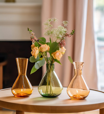 Beautiful fresh orange flowers bouquet in crystal glass vase on table in warm sunset sun lights against balcony windowの素材