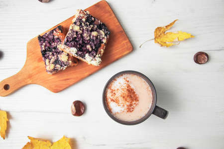 Piece of pumpkin pie with cinnamon and coffee with milk in brown dishes on  background with autumn yellow leaves - top view close up photography of seasonal american traditional sweet baked food.の写真素材