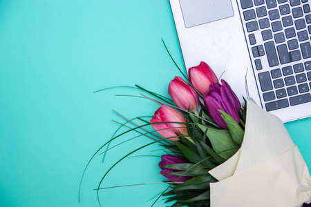 Computer with bouquet of blue on turquoise background.の写真素材