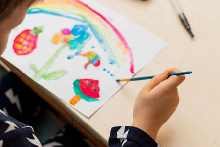 Cute boy doing homework, coloring pages, writing and painting. Children paint. Creative boy. hands painting, top view,の写真素材