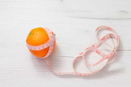 Measuring tape wrapped around orange on white background, Concept of the goal to lose weight, the goal of dietの写真素材