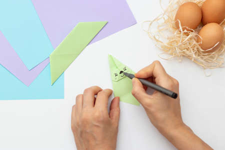 DIY Children's Easter craft bunny with an egg. Easter paper step by step instructions. Step 15. Happy bunny holds egg. Children's Art Project, needlework, crafts for children, springtimeの写真素材