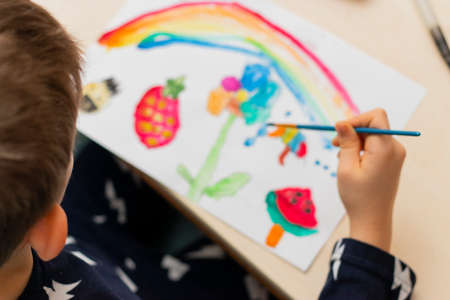 Cute boy doing homework, coloring pages, writing and painting. Children paint. Creative boy. hands painting, top view,の写真素材