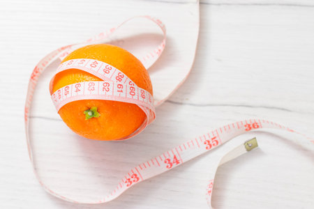 Measuring tape wrapped around orange on white background, Concept of the goal to lose weight, the...