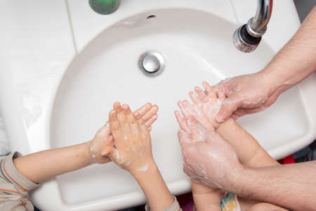 prevention of viruses. dad with son and daughter washing of hands soap foam and water. Disinfection against bacteria and viruses, protection against covid-19 diseaseの写真素材