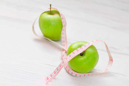 Measuring tape wrapped around two green apple isolated on white background, Concept of the goal to lose weight, the goal of diet,の写真素材