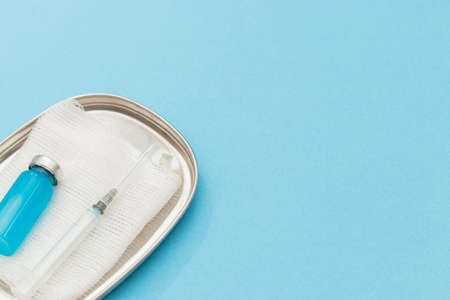 Concept of vaccination against coronavirus, medicine, injections, vaccination against covid-19. Bottle of vaccine on blue medical mask, syringe. Copy space. flat layの写真素材