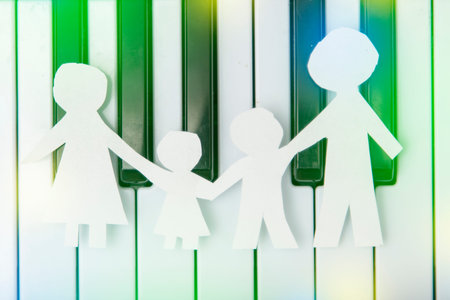 family made of paper, a symbol of a happy strong family, on the background of the piano keys....